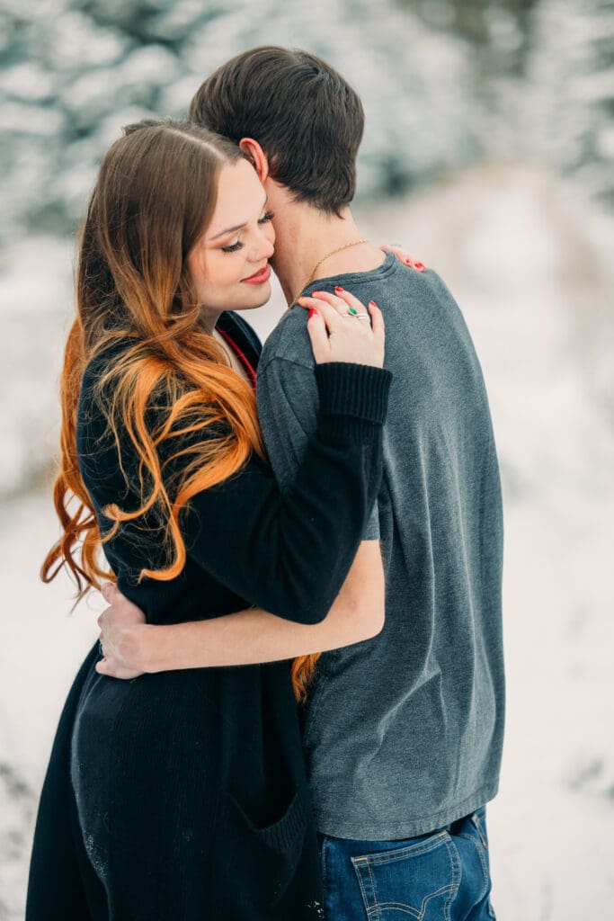 Couple embracing during a snowy engagement in Island Park, Idaho
