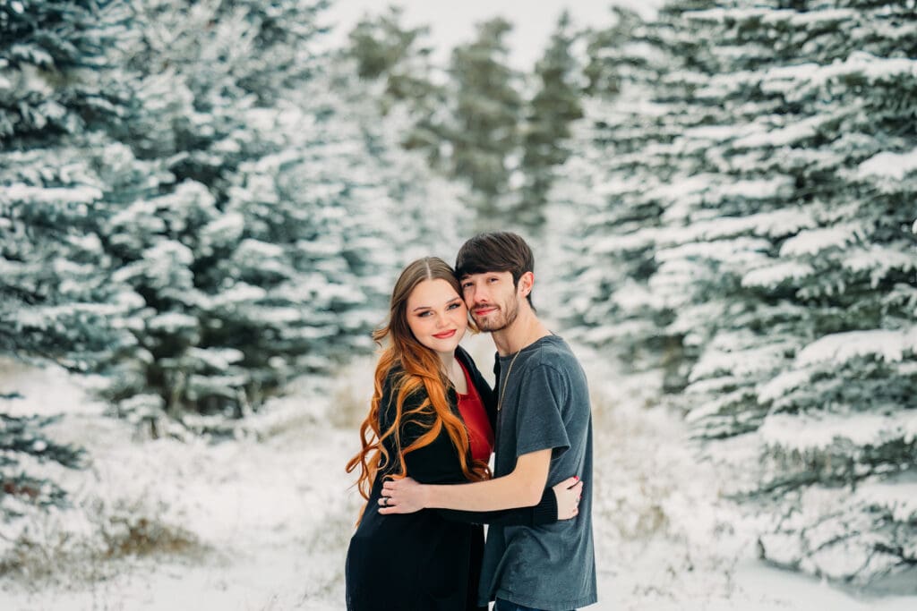 Couple embracing during a snowy engagement in Island Park, Idaho