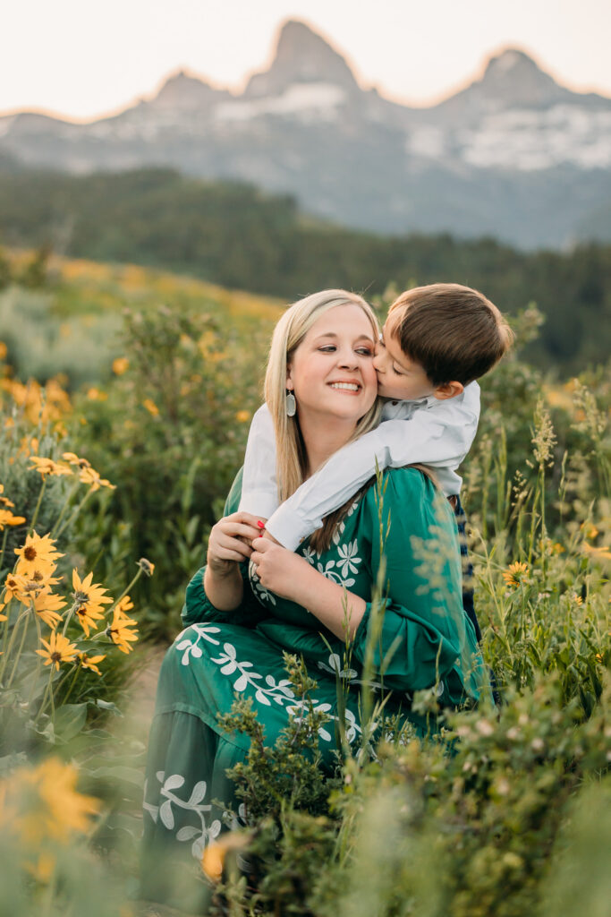Family of three embracing in a sunflower field during a sunrise session in Grand Teton National Park