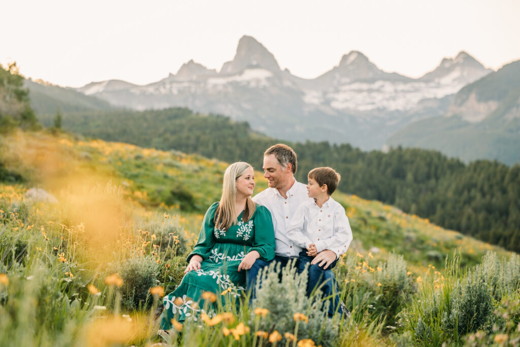 Family of three embracing in a sunflower field during a sunrise session in Grand Teton National Park