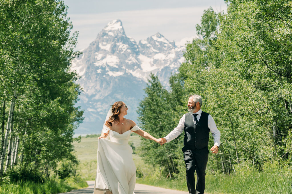 Bride and groom walking through alpine meadow in Grand Teton National Park after eloping