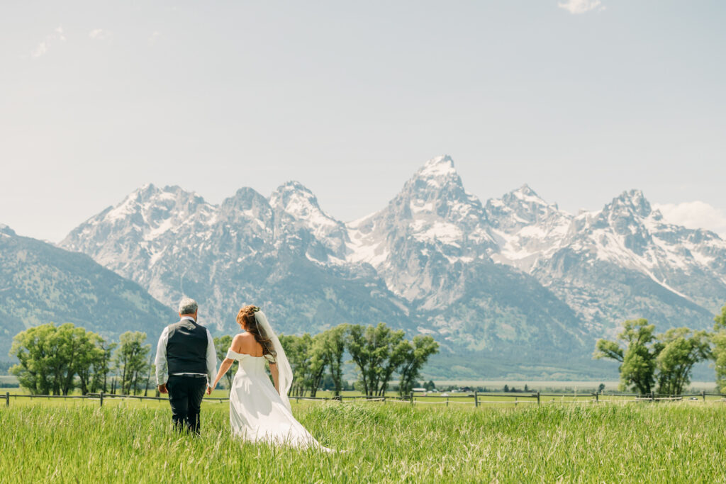 Bride and groom walking through alpine meadow in Grand Teton National Park after eloping