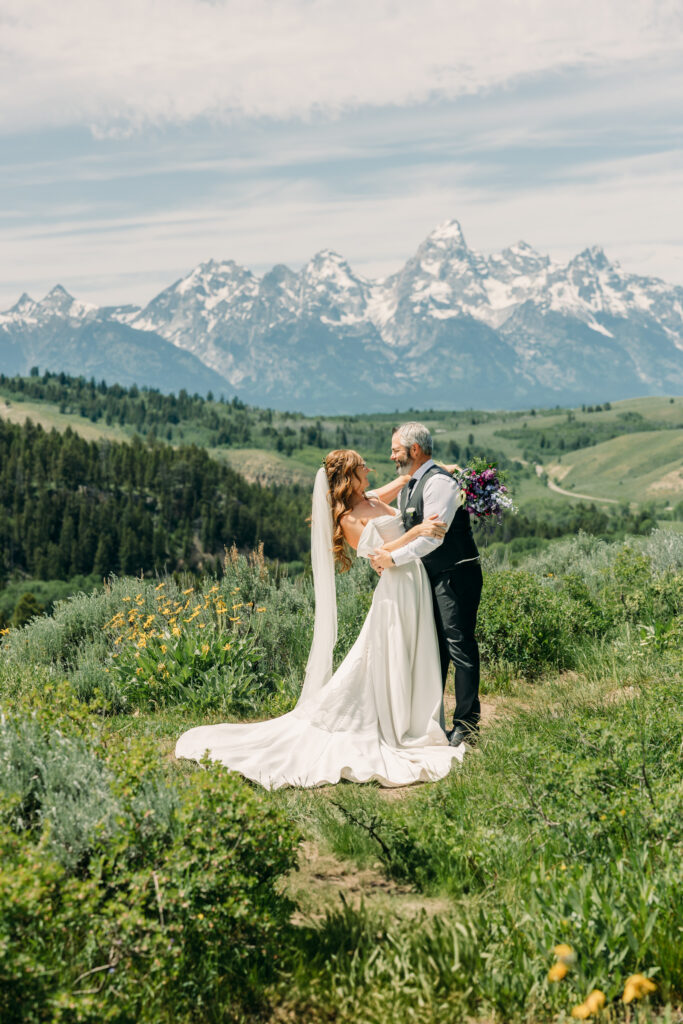 Wide landscape photo of bride and groom beneath the Tetons in Grand Teton National Park