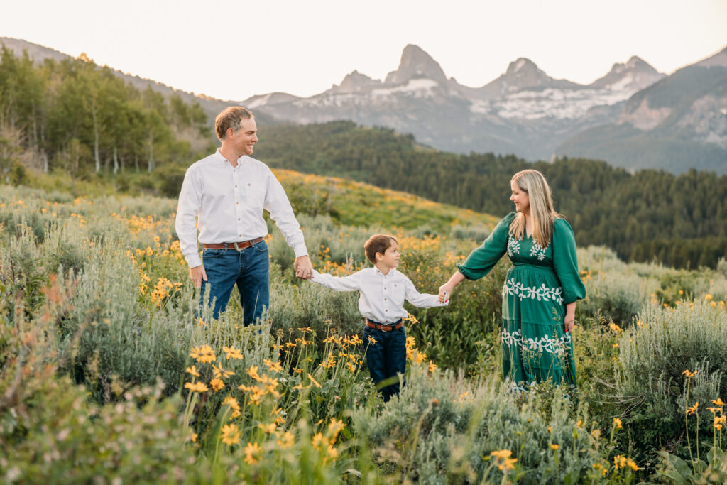 Grand Teton National Park family photographer documenting a joyful family of three at sunrise with the Tetons in the background.