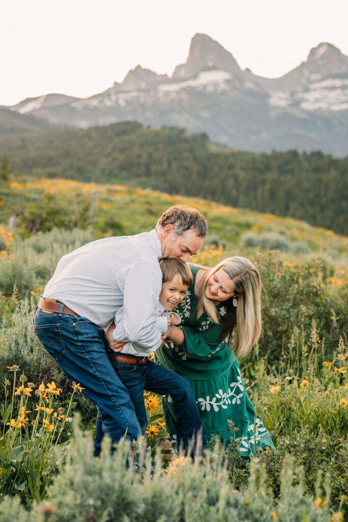 Grand Teton National Park family photographer documenting a joyful family of three at sunrise with the Tetons in the background.