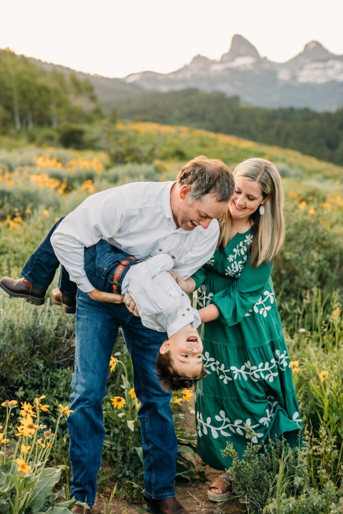 Grand Teton National Park family photographer documenting a joyful family of three at sunrise with the Tetons in the background.