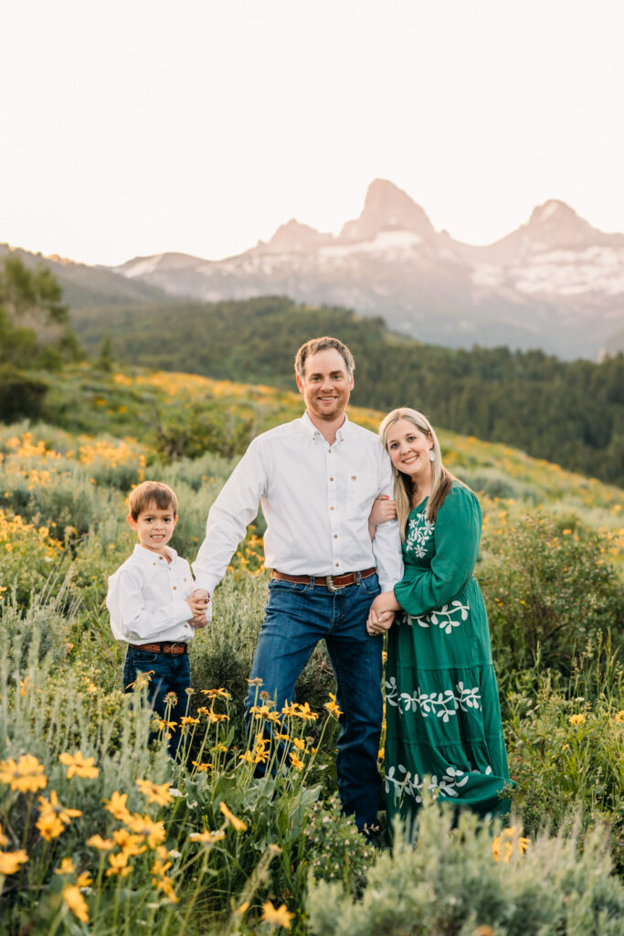 Grand Teton National Park family photographer documenting a joyful family of three at sunrise with the Tetons in the background.