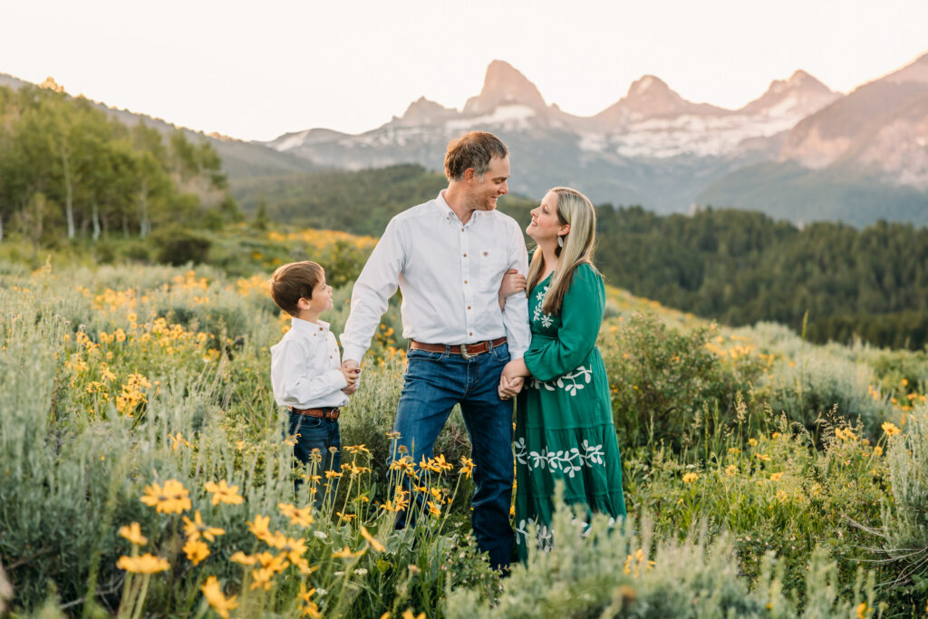 Grand Teton National Park family photographer documenting a joyful family of three at sunrise with the Tetons in the background.