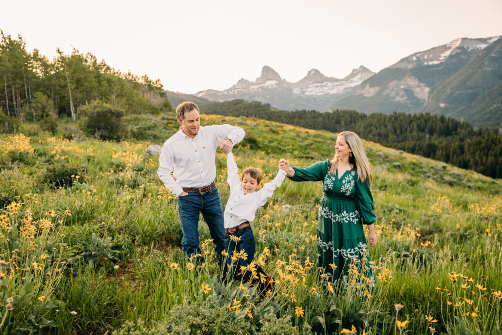 Grand Teton National Park family photographer documenting a joyful family of three at sunrise with the Tetons in the background.