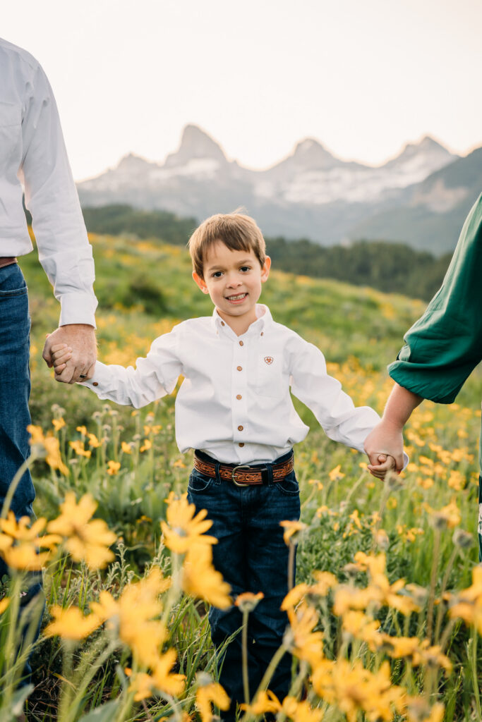 Grand Teton National Park family photographer documenting a joyful family of three at sunrise with the Tetons in the background.
