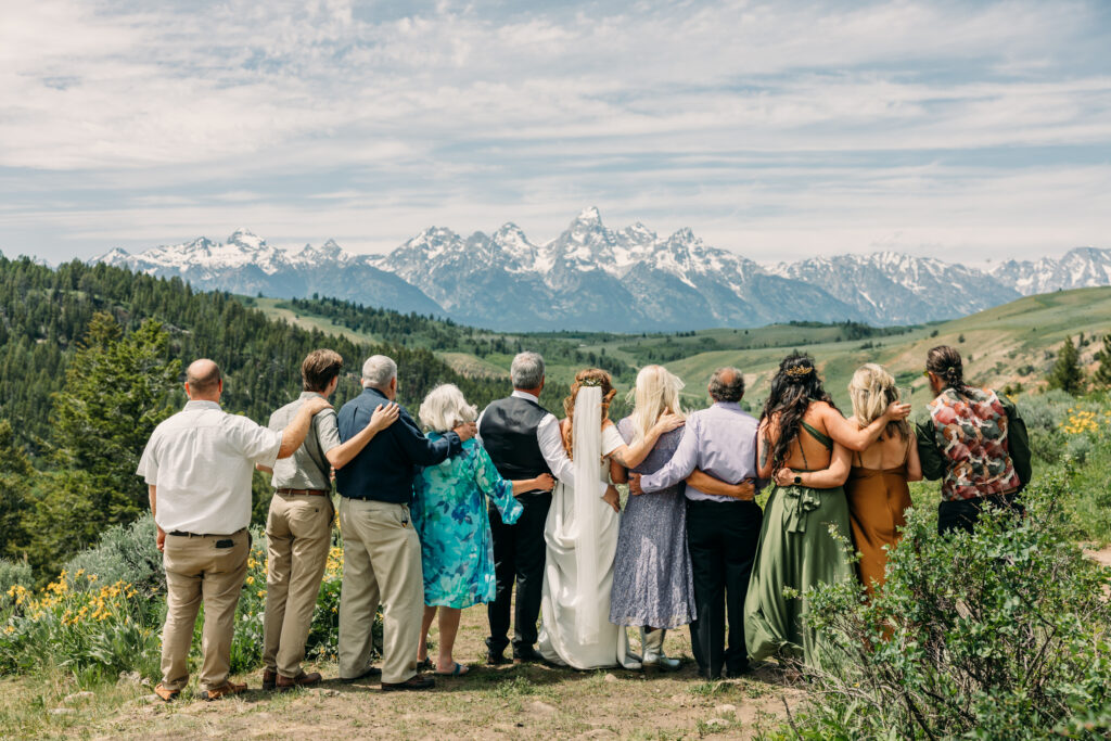 Bride and groom standing under The Wedding Tree with sweeping Teton mountain views