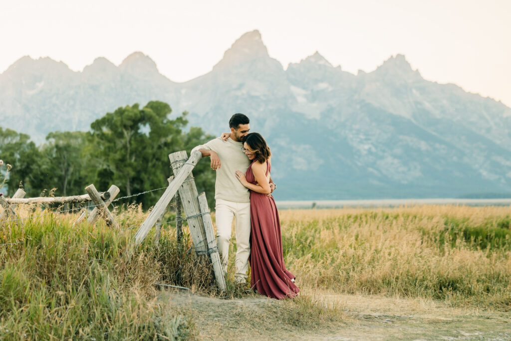 Couple in front of fence at Mormon Row for a photographer's guide to best places to take photos in Grand Teton