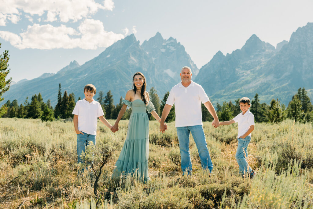 Family laughing in the meadow of Cathedral Turnout in Grand Teton surrounded by sagebrush