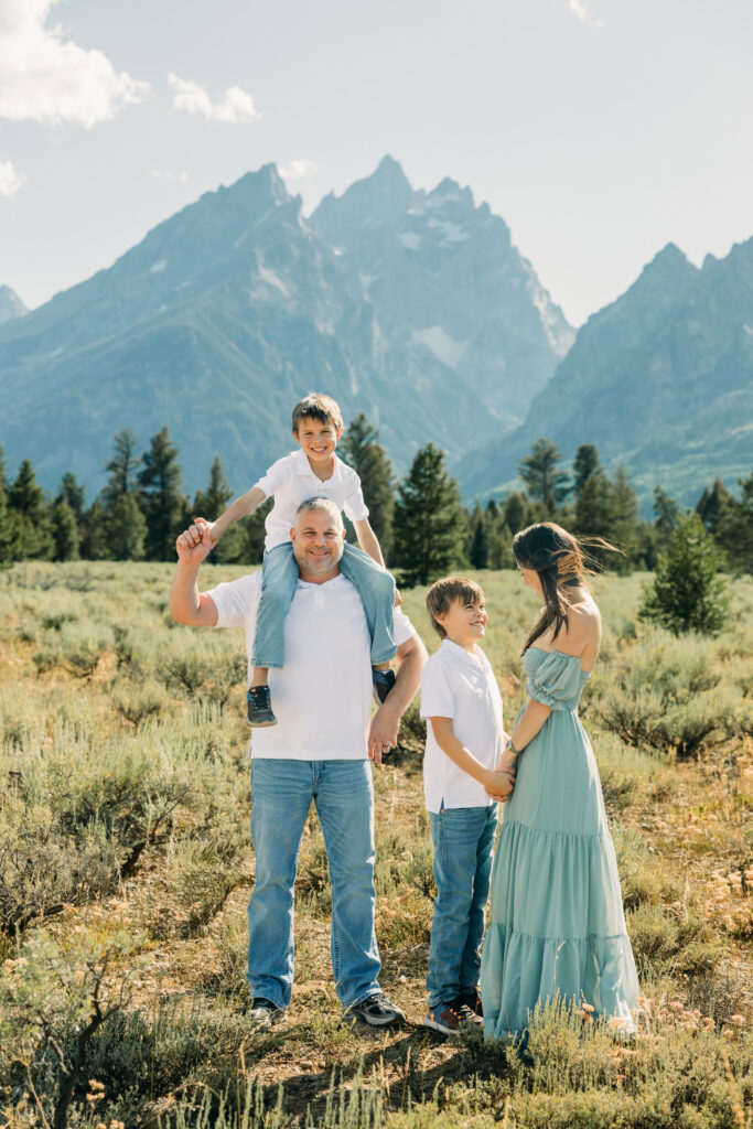 Family laughing in the meadow of Cathedral Turnout in Grand Teton surrounded by sagebrush