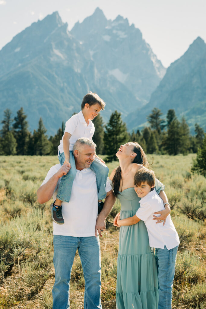 Family laughing in the meadow of Cathedral Turnout in Grand Teton surrounded by sagebrush