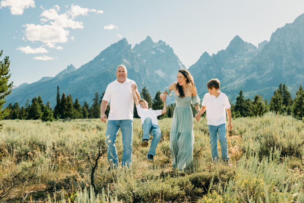 Family laughing in the meadow of Cathedral Turnout in Grand Teton surrounded by sagebrush