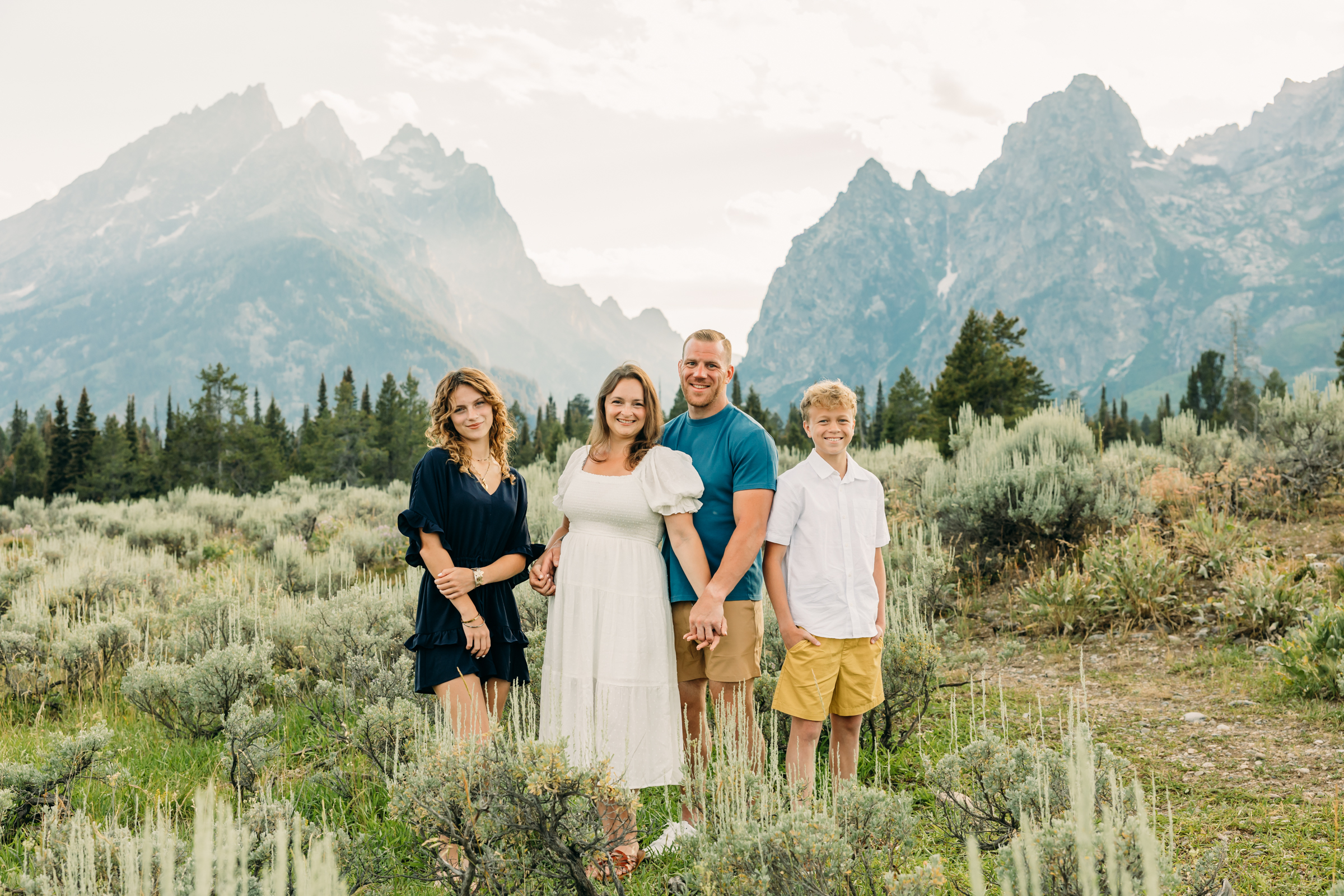 Mother and father hugging their kids during a mountain photo session in Grand Teton National Park Cascade Canyon Turnout
