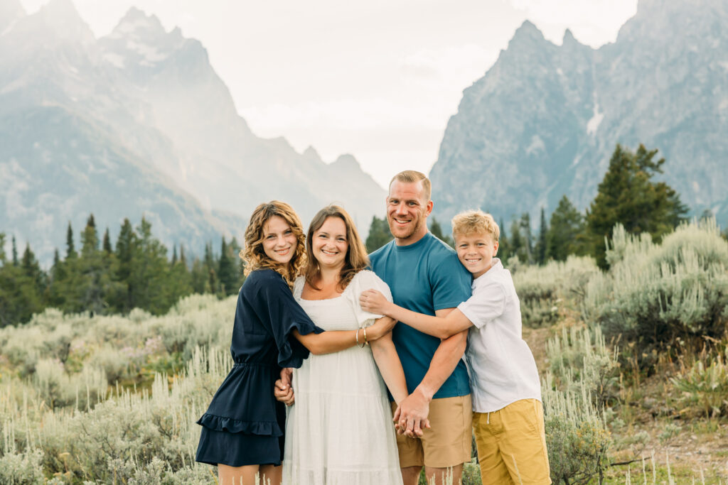Mother and father hugging their kids during a mountain photo session in Grand Teton National Park Cascade Canyon Turnout