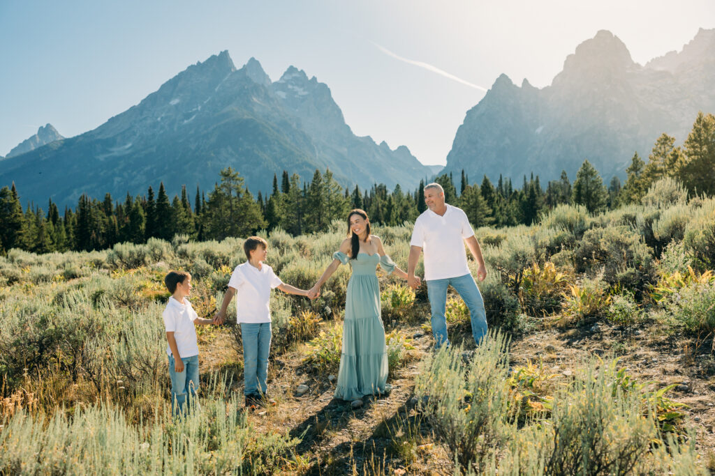 Jackson Hole family photographer afternoon session in the park with mountains in background and kids in meadow