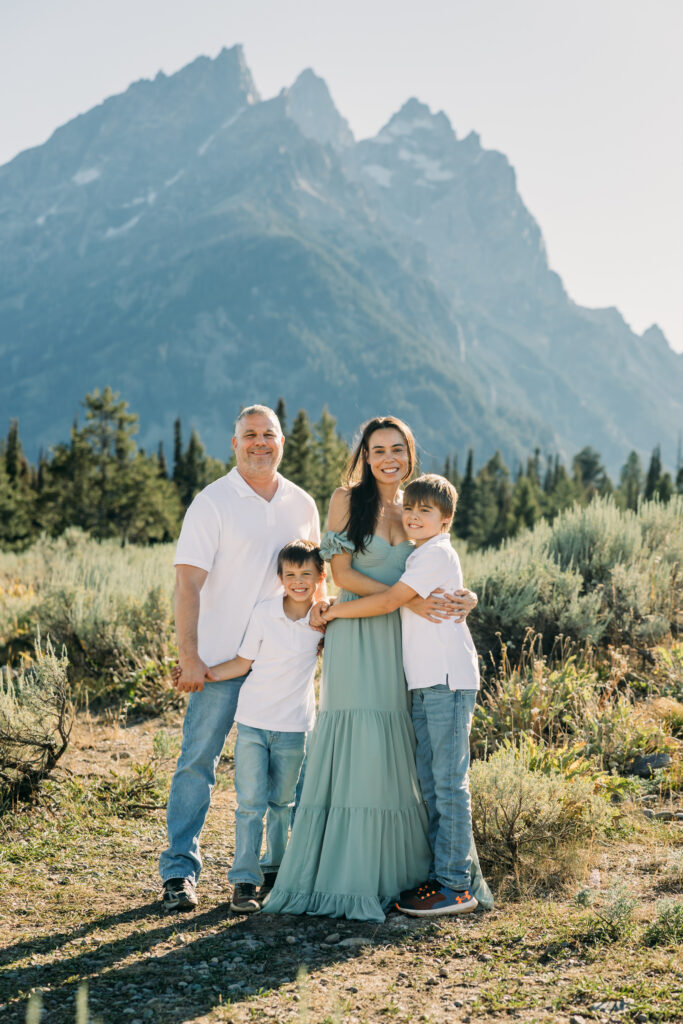 Jackson Hole family photographer afternoon session in the park with mountains in background and kids in meadow