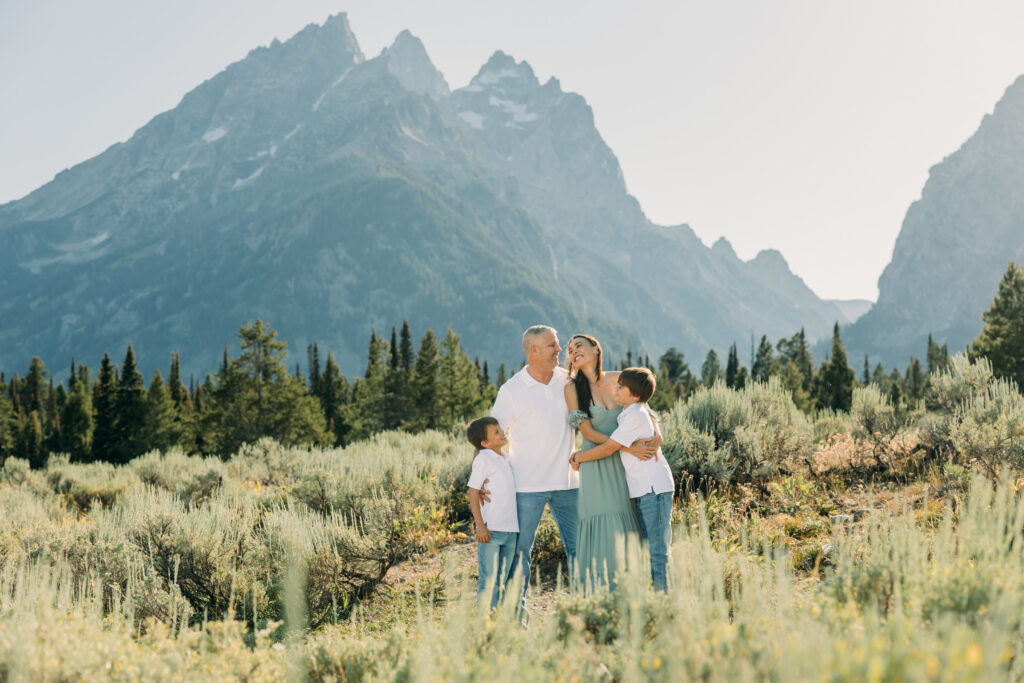 Jackson Hole family photographer afternoon session in the park with mountains in background and kids in meadow